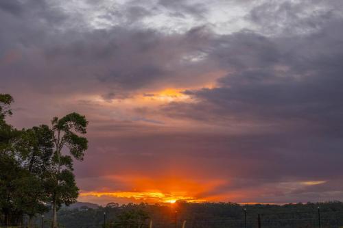 a cloudy sky with the sun setting in the distance at Saddle House by Tiny Away in Lower Beechmont