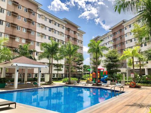 a pool at a hotel with a playground and palm trees at Apparate Staycation in Hope Residences - Trece, Cavite, Philippines in Cavite