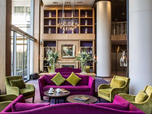 a living room with purple furniture and a chandelier at Sofitel Strasbourg Grande Ile in Strasbourg