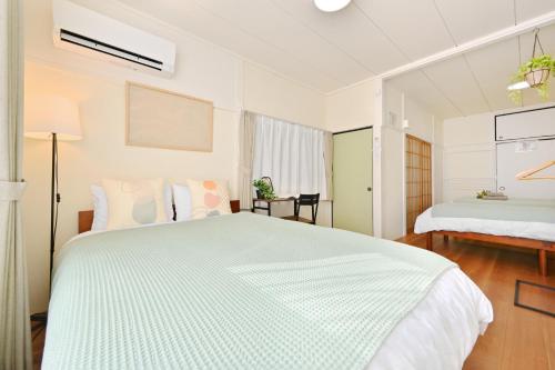 a white bedroom with a large bed and a window at INUYAMA BASE Vacation rental in Inuyama