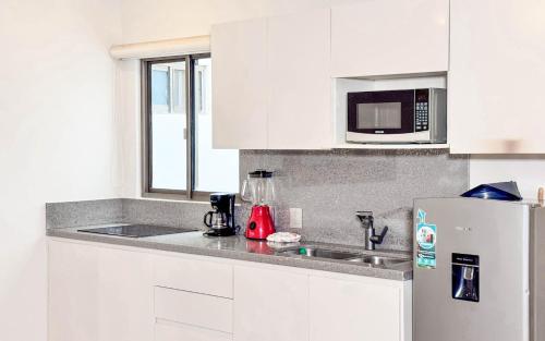 a white kitchen with a sink and a refrigerator at Grand Boréna Hotel Boutique in Playa del Carmen