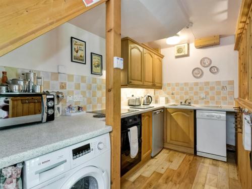 a kitchen with wooden cabinets and a washer and dryer at Annexe- Ukc4917 in Timberscombe