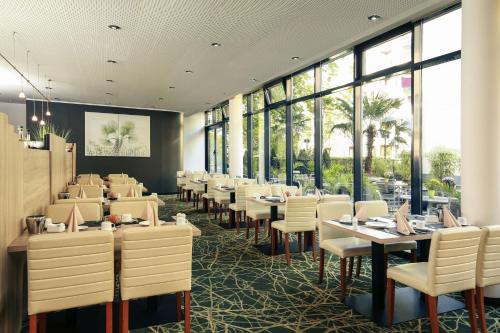 a dining room with tables and chairs and windows at Mercure Hotel Plaza Essen in Essen