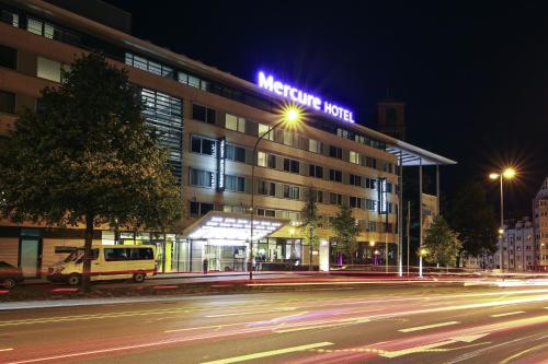 a hotel building with a neon sign on it at night at Mercure Hotel Plaza Essen in Essen