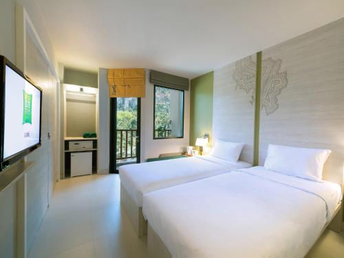 two beds in a room with a flat screen tv at ibis Styles Krabi Ao Nang in Ao Nang Beach