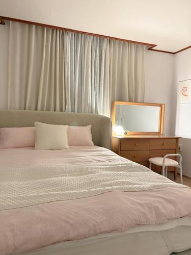 a bedroom with a bed and a dresser and a mirror at juns house in Ulsan