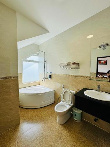 a bathroom with a tub and a toilet and a sink at Tommy hotel khe sanh dalat in Da Lat
