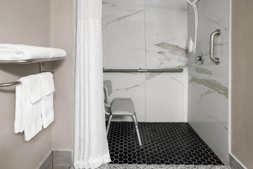a shower with a glass door with a chair in a bathroom at Super 8 by Wyndham Mentor/Cleveland Area in Mentor