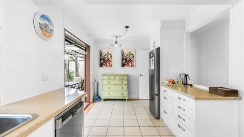 a kitchen with white cabinets and a stainless steel refrigerator at Coastal Palms Hideaway in Bongaree