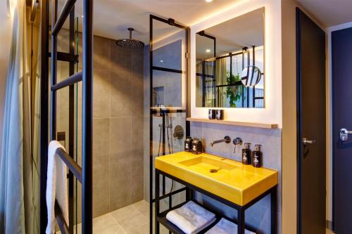 a bathroom with a yellow sink and a shower at Me and All Hotel Ulm, by Hyatt in Ulm