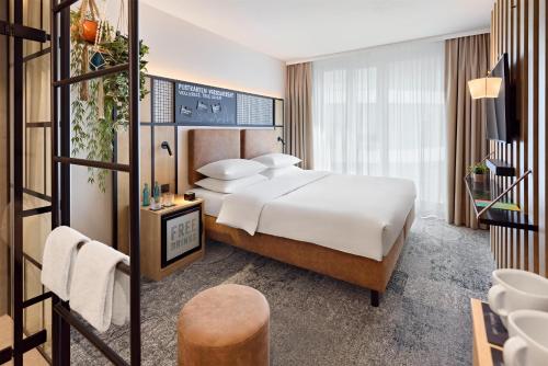 a hotel room with a large bed and a bathroom at Me and All Hotel Ulm, by Hyatt in Ulm