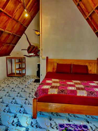 a bedroom with a bed with a red comforter at Sumatra Thomas Leaf Monkey Guesthouse & Jungle Trek in Bukit Lawang