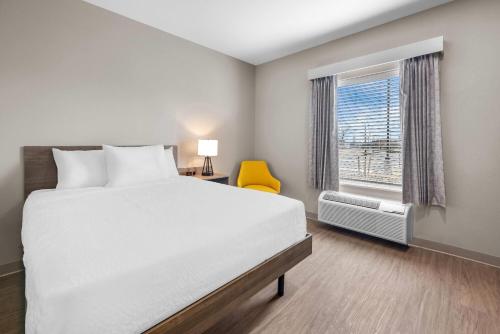 a bedroom with a white bed and a window at ECHO Suites Extended Stay by Wyndham Colorado Springs Airport in Colorado Springs