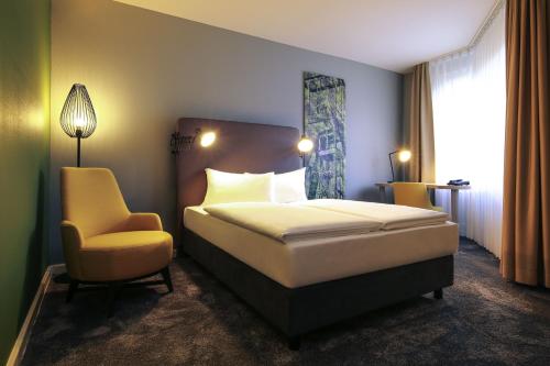 a hotel room with a bed and a chair at Mercure Hotel Plaza Essen in Essen