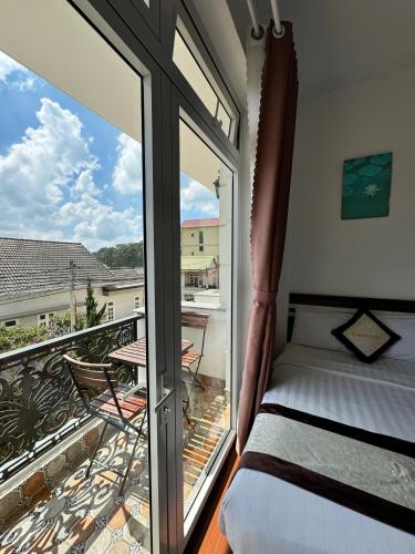 a bedroom with a bed and a balcony with a view at Tommy hotel khe sanh dalat in Da Lat
