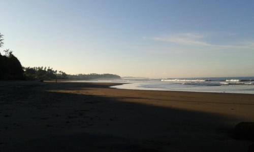 an empty beach with the ocean in the background at Pondok Pisces Bungalows Balian Beach in Selemadeg