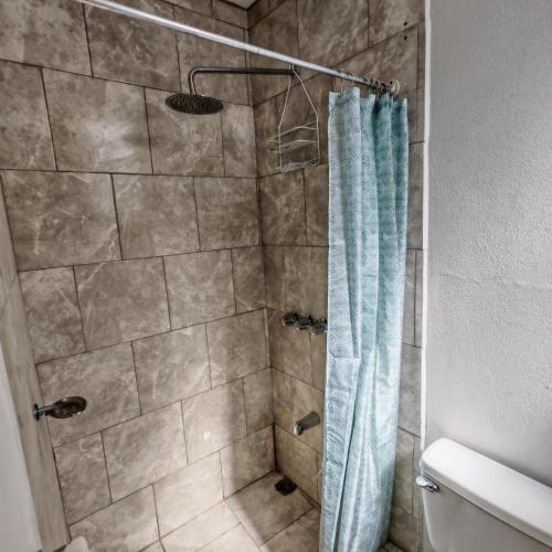 a shower with a blue shower curtain in a bathroom at Apartamentos Las Orquideas in San Pedro