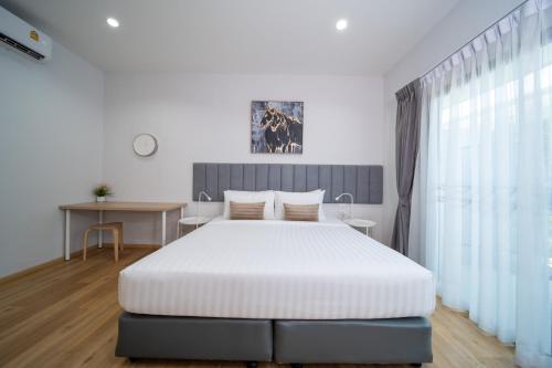a bedroom with a large white bed and a table at Xen Pool Access Phuket in Chalong