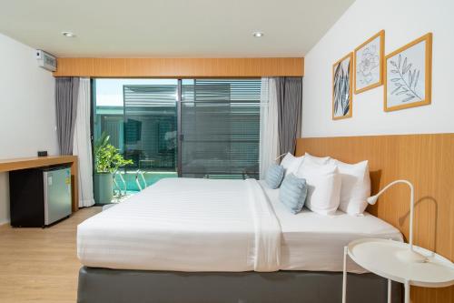 ein Schlafzimmer mit einem großen weißen Bett und einem Fenster in der Unterkunft Xen Pool Access Phuket in Chalong 