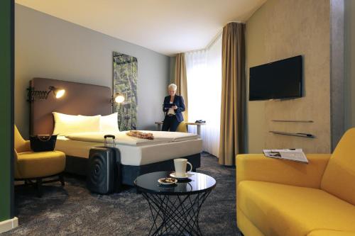 a hotel room with a bed and a woman standing in the window at Mercure Hotel Plaza Essen in Essen