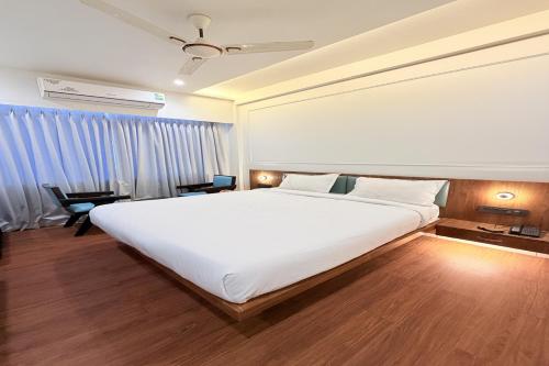 a bedroom with a large white bed and blue curtains at The Shivanta Inn in Ābu Road