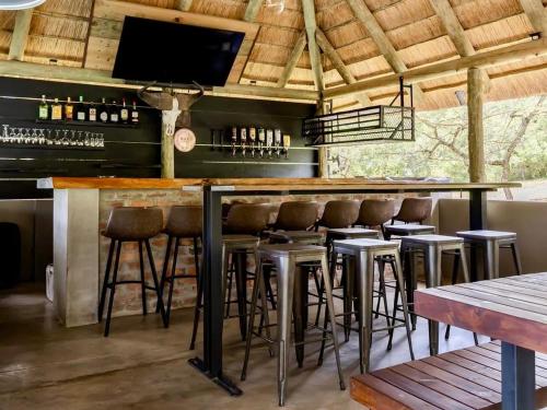 a bar with stools and a flat screen tv at Syeta Bush Lodge - Sunset View in Nelspruit