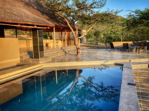 a swimming pool in front of a villa at Syeta Bush Lodge - Sunset View in Nelspruit