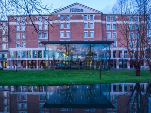 a building with a reflection in the water at Hilton London Heathrow Airport Terminal 5 in Hillingdon