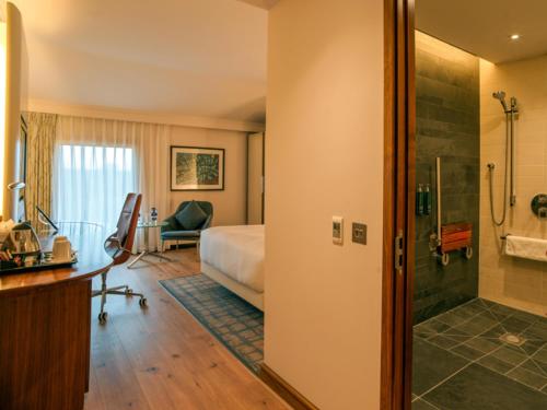 a hotel room with a bed and a shower at Hilton London Heathrow Airport Terminal 5 in Hillingdon