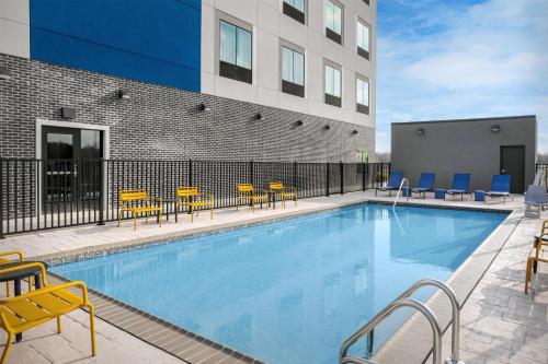 a swimming pool with chairs and a building at Hampton Inn By Hilton Clanton in Clanton