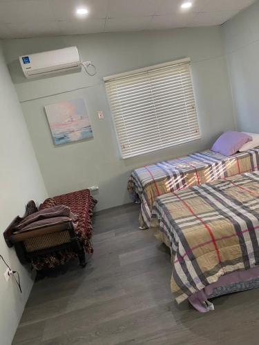 a room with two beds and a window in it at Beverley Manor DIAMOND VALE' 2 Bedroom 1 Bath Apartment in Diego Martin