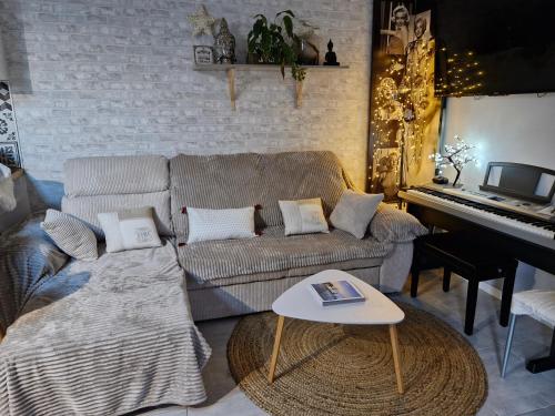 a living room with a couch and a piano at Mon havre de paix in Blésignac