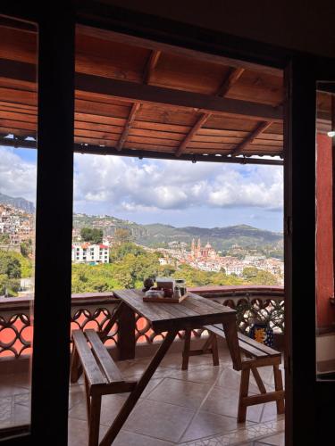 a table and benches on a balcony with a view at Entre el sol y la luna in Taxco de Alarcón
