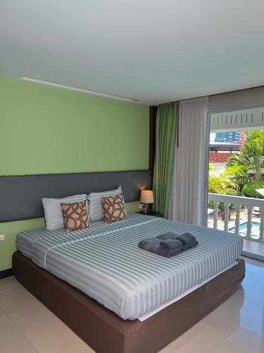 a bedroom with a large bed with a large window at Windmill Resort Hotel Pattaya in North Pattaya
