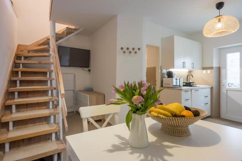 a kitchen with a vase of flowers and a bowl of fruit on a table at Veli Lošinj Old Town Apartments in Veli Lošinj