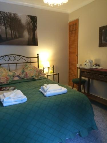a bedroom with a green bed with towels on it at The Bryntirion Inn in Bala