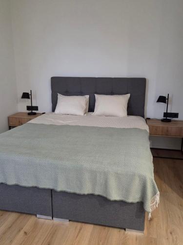 a bedroom with a large gray bed with two lamps at Peetri Plats Border Apartmens in Narva