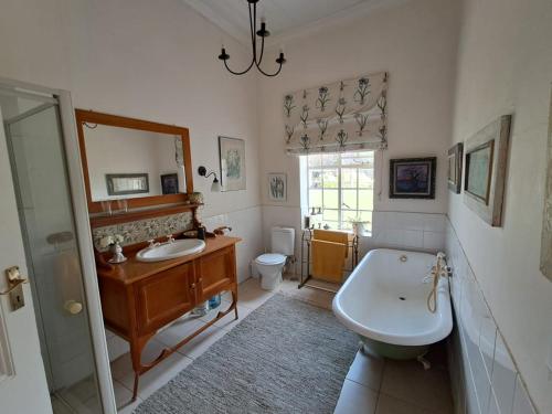 a bathroom with a tub and a sink and a toilet at Country Barns Guest house in Wakkerstroom