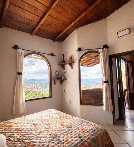 a bedroom with two windows and a bed in it at Entre el sol y la luna in Taxco de Alarcón