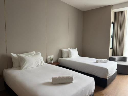 a hotel room with two beds and a chair at Roxy Hotel & Apartment Lawas in Lawas