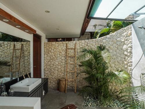 a bathroom with a tub and a sink and a plant at Biu Biu Resort Bali in Jimbaran