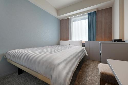 a bedroom with a bed and a window at Keio Presso Inn Shinjuku in Tokyo