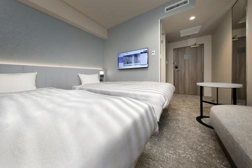 a hotel room with two beds and a table at Keio Presso Inn Shinjuku in Tokyo