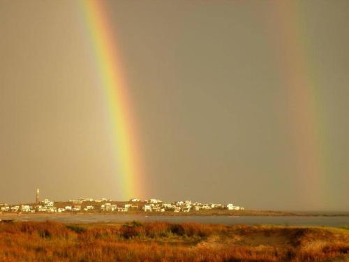 a rainbow in the sky over a city at cabopolonioalojamiento in Cabo Polonio