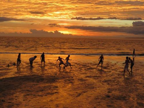 a group of people playing on the beach at sunset at cabopolonioalojamiento in Cabo Polonio