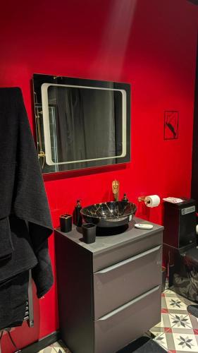 a bathroom with a sink and a red wall at L'instant Désir love room jacuzzi in Ferrières