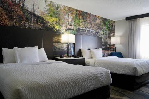 a hotel room with two beds and a painting on the wall at Clarion Pointe Fairborn near Wright Patterson AFB in Fairborn