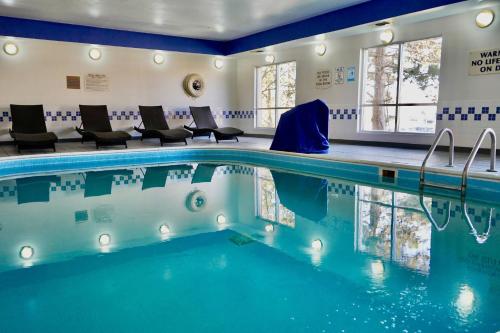 a swimming pool in a hotel room with chairs at Clarion Pointe Fairborn near Wright Patterson AFB in Fairborn