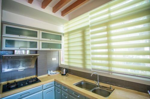 a kitchen with blue cabinets and a sink and windows at Yalong Sea Joy in Sanya