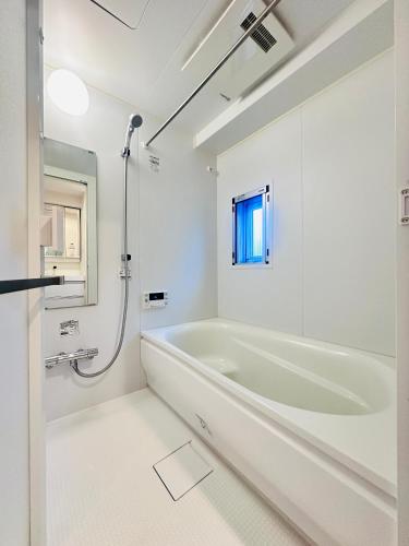 a white bathroom with a tub and a shower at REGNO COMFORT ASAKUSA Ⅳ in Tokyo
